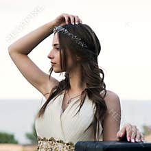 Summer portrait of young beautiful lady wearing long white evening dress posing in the park.
