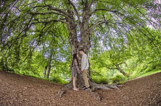 Millennial couple face to face under a big tree