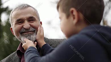 Grandson touches the beautiful beard of his grandfather