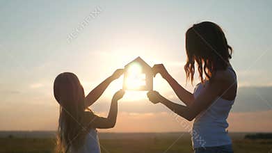 Silhouette happy mother and daughter with dream house. Paper house as a symbol. The concept of family happiness.