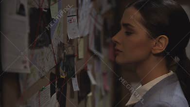 Smart scientist looking attentively at the investigation board, evaluating clues