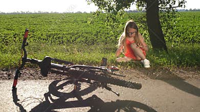 Teenage girl sitting on road after bicycle crash