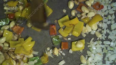 Cook cooking garlic and sweet peppers in olive oil on hot pan top view. Close up garlic, and onion bulgarian pepper