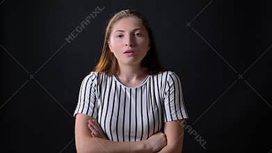 Furious young woman standing with crossed hands and looking at camera with angry and concerned expression, black
