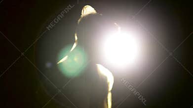 Male silhouette in yellow cloak with red balloon in his hand in dark