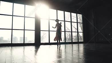 Ballet dancer dancing a classical ballet in pointe shoes on the background of a large window. Elegant ballerina in
