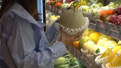 Woman choose Melon, which is placed on the shelf