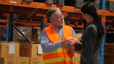Senior engineer talking with businesswomen and shake hands in warehouse