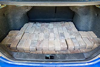 Stacked grey bricks loaded in the trunk of a car