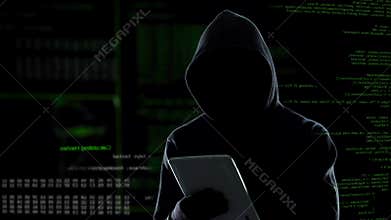 Cyber attack with unrecognizable hooded hacker using tablet computer, cybercrime