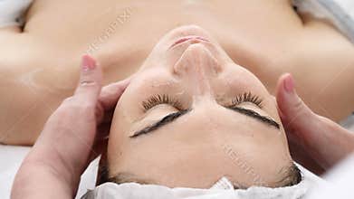 Beauty clinic. Young woman gets professional facial procedure. Beautician makes massage on female face and chest. face