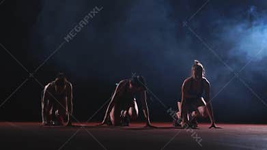 Female runners at athletics track crouching at the starting blocks before a race. In slow motion.