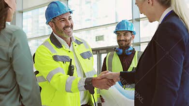 Mature architect and contractor shaking hands at construction site