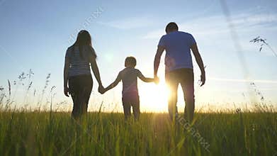 Happy family walks in the park in the sun at sunset. Mom, dad and kid happy walk at sunset in the park. Joint family
