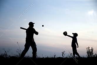 Silhouette of father and son playing baseball on nature family sport