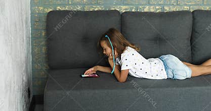 Child using cellphone on the sofa in modern and bright apartment