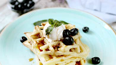 Presentation Fresh baked homemade classic Belgian waffles topped with icecream, fresh blueberries and mint on wooden background