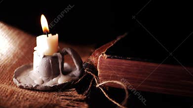 Ancient worn book and candle on dark background