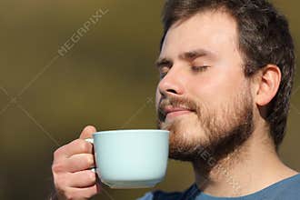Man smelling coffee aroma outdoors