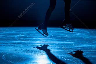 The female athlete in figure skating at the moment of the jump. Women's legs in white skates for figure skating