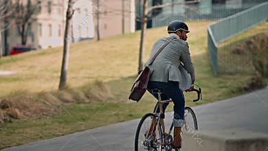 Rear back view businessman going to work on e-bike. Eco friendly transport.