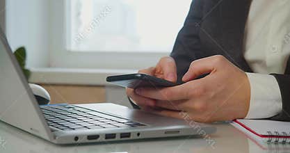Procrastination - Female hands with a smartphone in front of a laptop monitor. A woman actively communicates online or