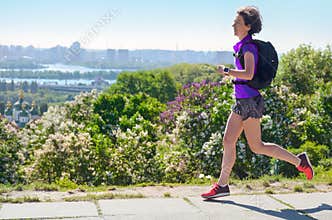 Active woman runner run commutes to work with backpack, city morning run commuting and healthy lifestyle concept, skyline of Kyiv