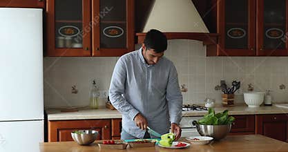 Young handsome man move to music cooking in kitchen