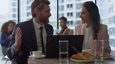 Motivated business group discuss project success using laptop computer in cafe.