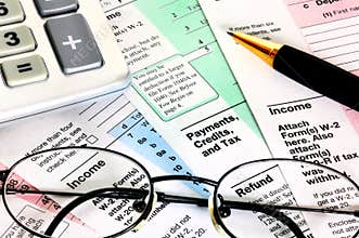 Financial papers with calculator, glasses and pen