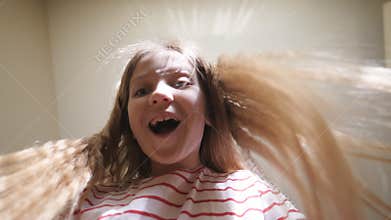 Happy small girl with blonde hair opening carton package with positive emotions while at room. Beautiful female child