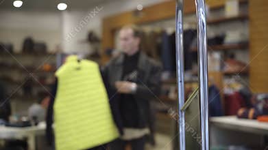 Shoplifting scanner at shop entrance with blurred man choosing clothes at the background. Male Caucasian thief taking
