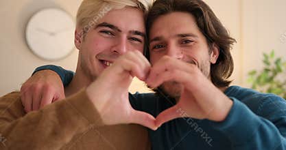 Gay couple embracing and gesturing love sign with hands