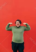 Vertical shot of a strong young fat hispanic man demonstrating his power by raising his hands and clenching his fists, showing