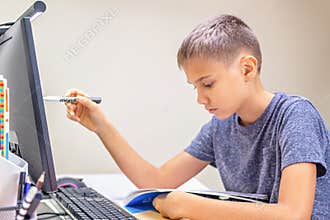 Teenage boy with computer having video call, virtual online leasson, making homework at home