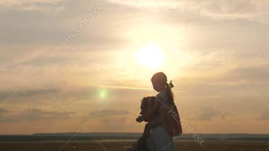 Daddy walks with his daughter on his shoulders in rays of sunset. Father and kid play. Happy family resting in park. Dad