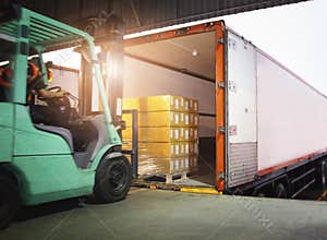 Forklift Driver Loading Package Boxes into Cargo Container. Cargo Trailer Truck Parked Loading at Dock Warehouse.