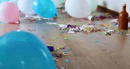 Floor with after party celebration with empty bottles, wine glass and party decorations