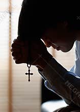 Asian man bowing his head on the Bible and carrying a cross. According to the beliefs of Christianity Is the salvation of Jesus.