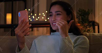 Woman video chatting using mobile phone sitting on sofa