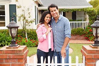 Hispanic couple standing outside new home