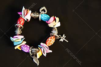 Beautiful bracelet for hand with metal ornaments in the form of heart, cross, and colored shells