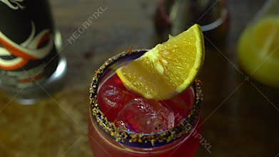 Red alcoholic beverage in glass goblet with an orange slice