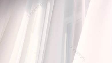 Bright morning sun in the open window through the curtains. Abstract white waving curtain in white bedroom apartment.