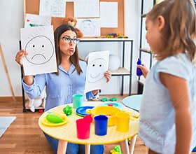 Young therapist woman speaking and treating child, counselor and behaviour correction at pedagogue payroom showing happy and sad