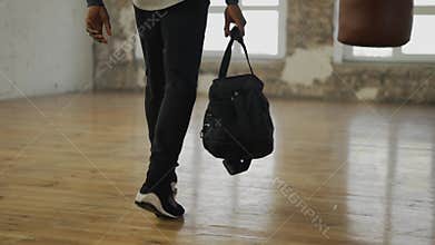Cropped view of an athlete walking into room with a bag, ready to start training