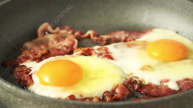 Keto meal fried eggs with fat bacon, two yellow yolk frying with pork, ketogenic diet