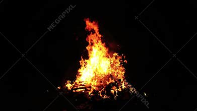 Raging bonfire dark night blazing fiercely glowing orange high flames