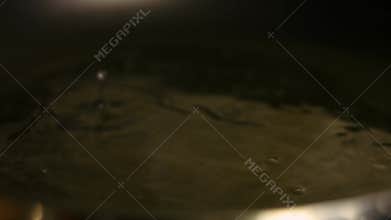 Female chef pouring a glass of water into a frying pan. Preparing the sauce for chicken. Process of cooking shkmeruli -