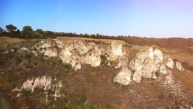 Drone closing up on a mountainside, rocky hill with the cliff.